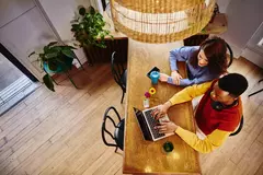 Bird view of a female and male working on a laptop at a table